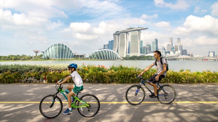ผู้คนขี่จักรยานใน Marina Bay Sands® โดยมี Flower Dome เป็นฉากหลัง