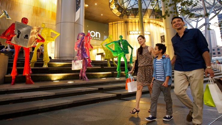 ครอบครัวเดินผ่าน ION Orchard พร้อมถุงช้อปปิ้ง