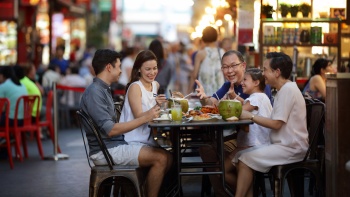 ครอบครัวกำลังเอร็ดอร่อยกับอาหารที่มีให้เลือกมากมายที่ Chinatown Food Street Singapore