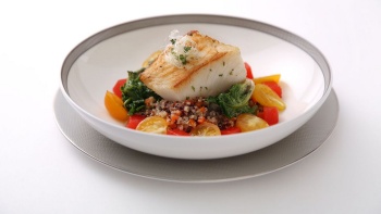 Plate of seared fish fillet on a bed of vegetables