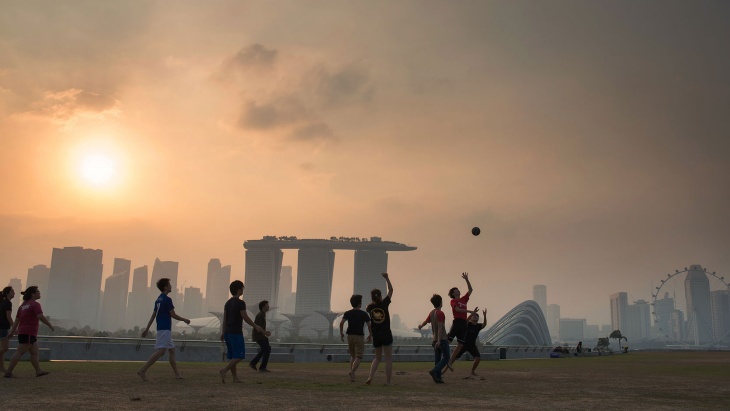 Những cậu bé chơi bóng đá tại Đập nước Marina Barrage trong khung cảnh hoàng hôn trên nền màn sương mờ ảo của Vịnh Marina