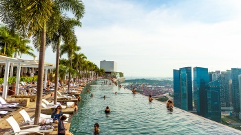 Quang cảnh hồ bơi vô cực trên Marina Bay Sands<sup>®</sup> SkyPark, với tầm nhìn ra đường chân trời Singapore vào buổi chiều