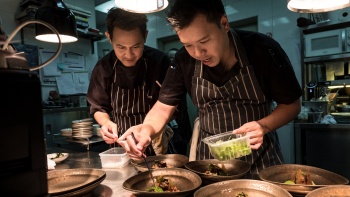 Two chefs plating dishes in the kitchen of Labyrinth