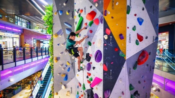 A man scaling the rock climbing facility at Funan