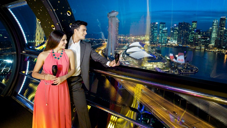 Một cặp đôi ngắm nhìn đường chân trời Singapore vào buổi tối từ khoang của Vòng quay Singapore Flyer