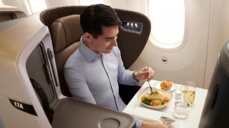 Hành khách nam trong khoang hạng Thương gia của Singapore Airlines ăn trên máy bay